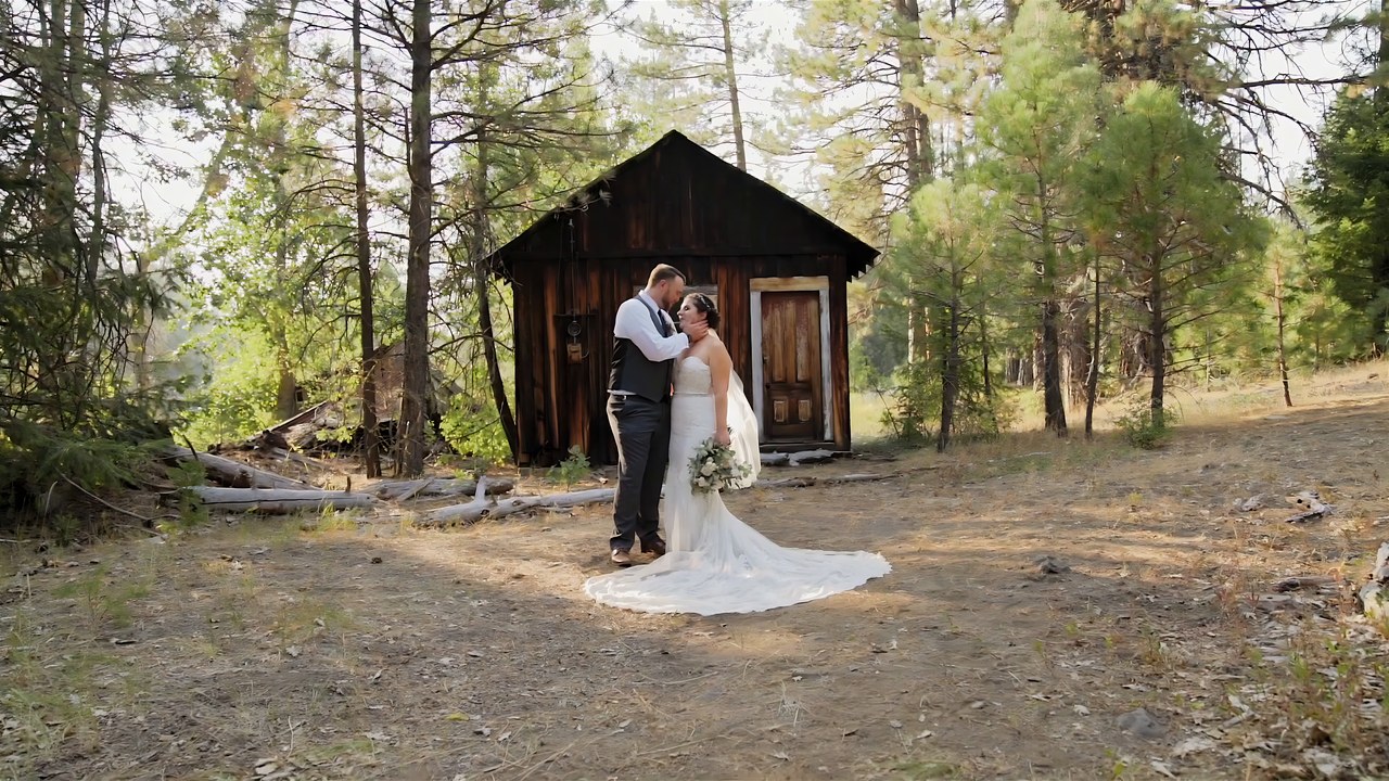 Jessie and Jeff hold each other beside an old wooden cabin
