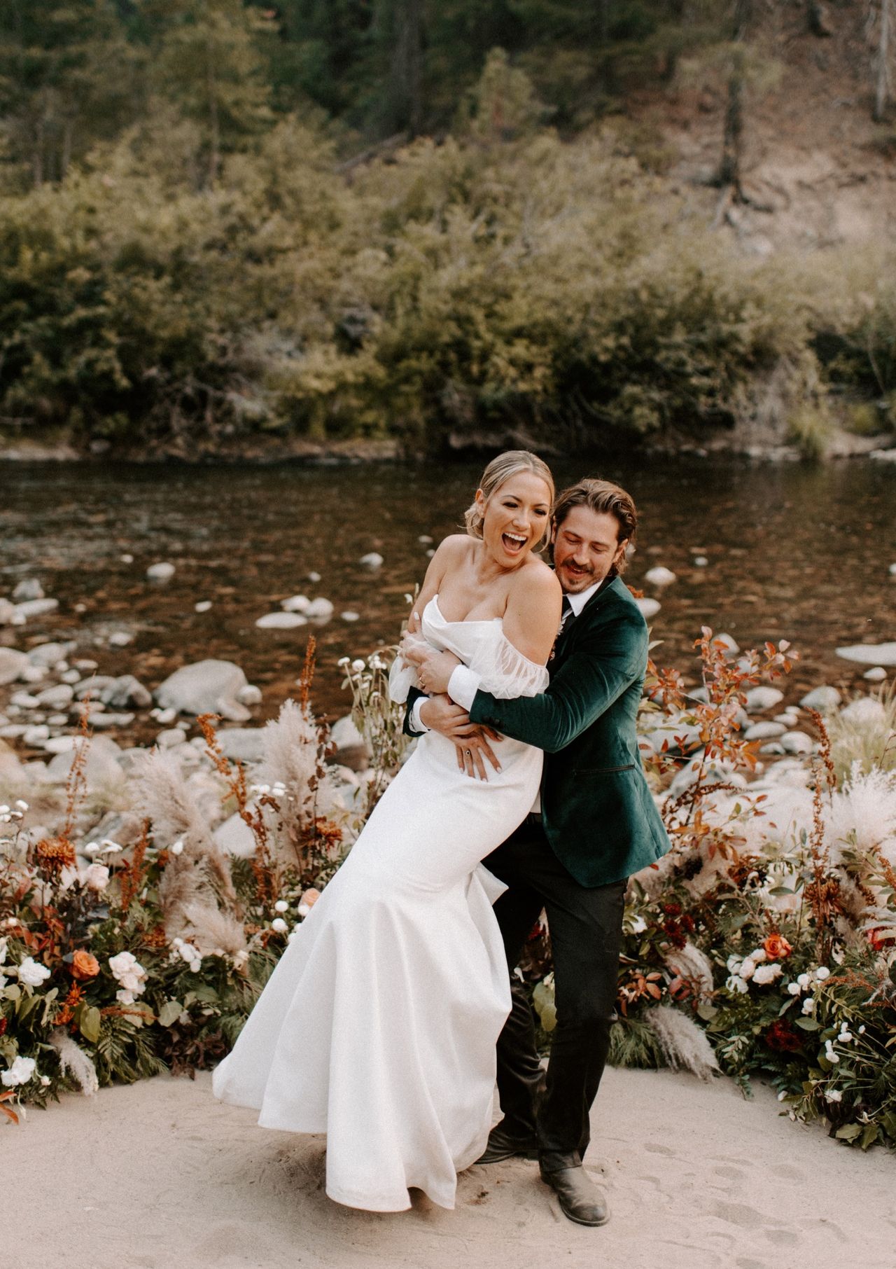 Joan laughs as Kyle lifts her beside the river
