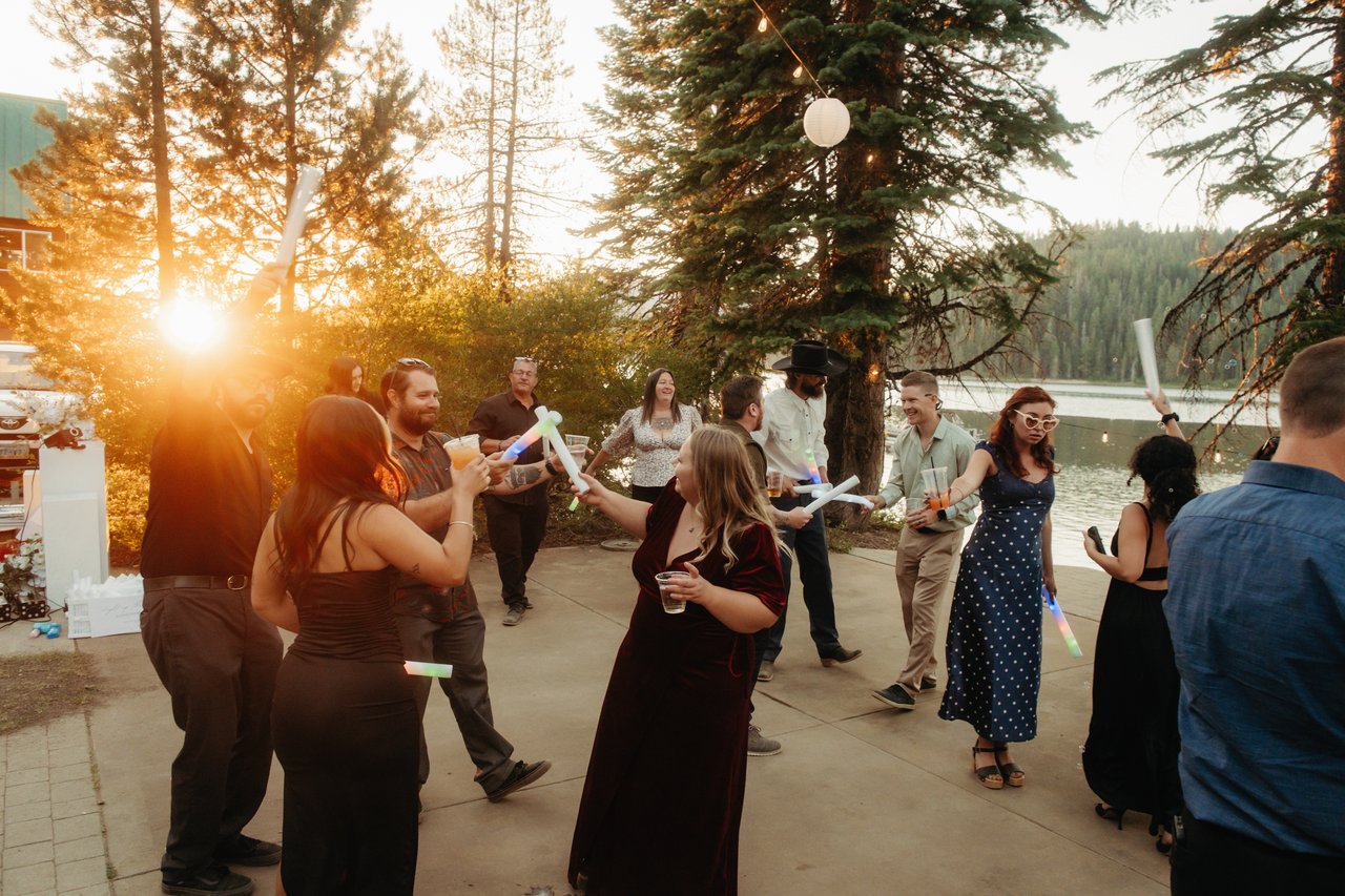 The low sun bursts through the pines over guests dancing beside Bucks Lake