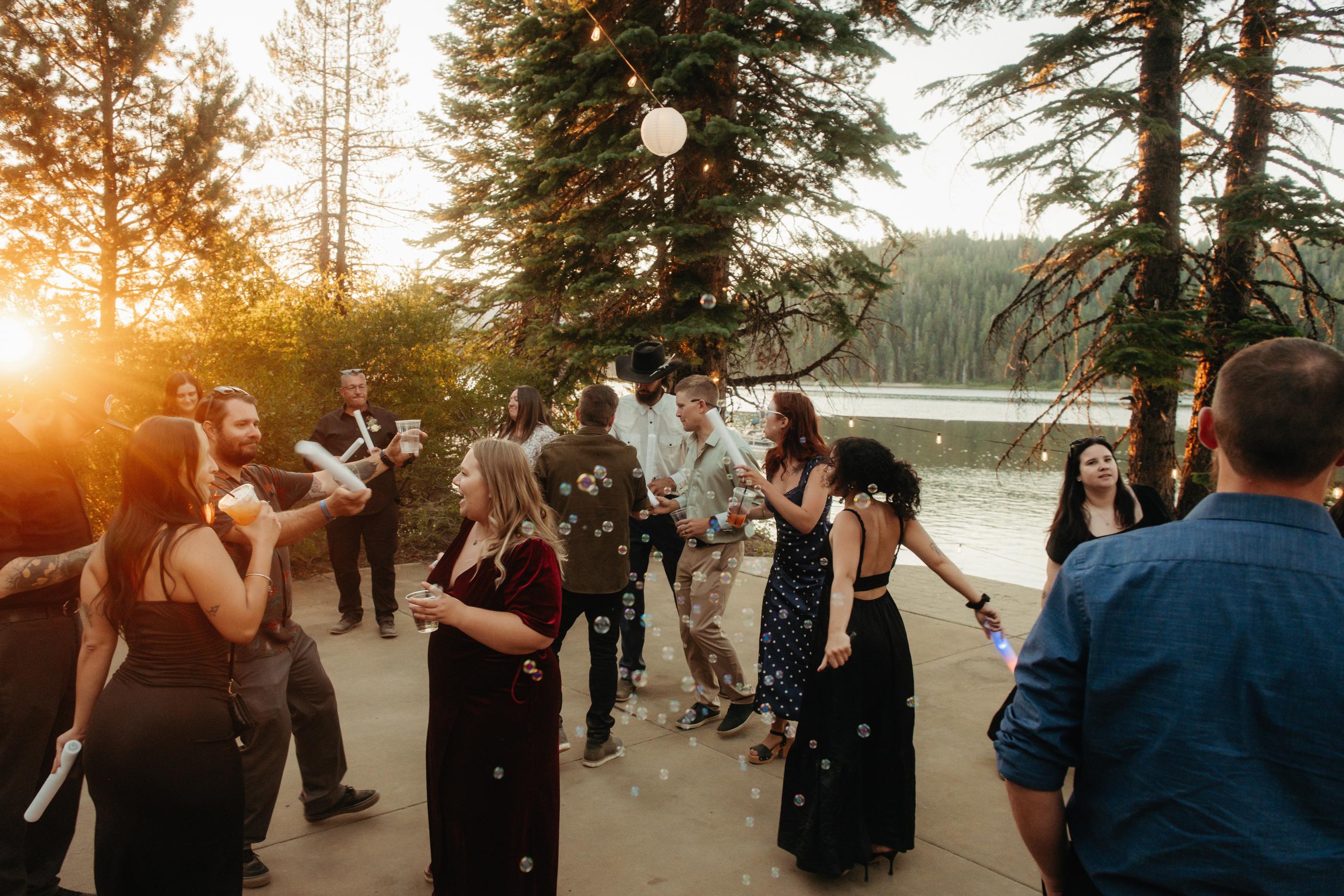 Guests dance through drifting bubbles at golden hour on the lakeside patio at The Lakeshore Resort on Bucks Lake