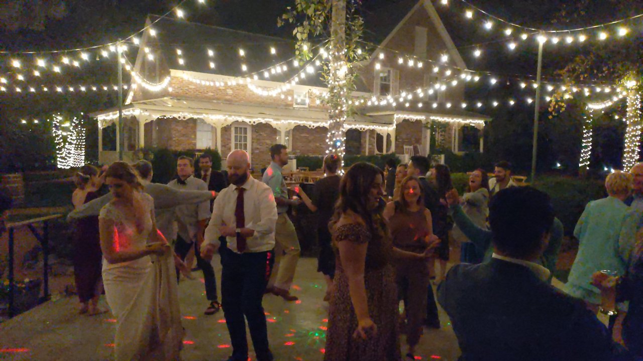 Lauren and Mark dance with their guests under the string lights