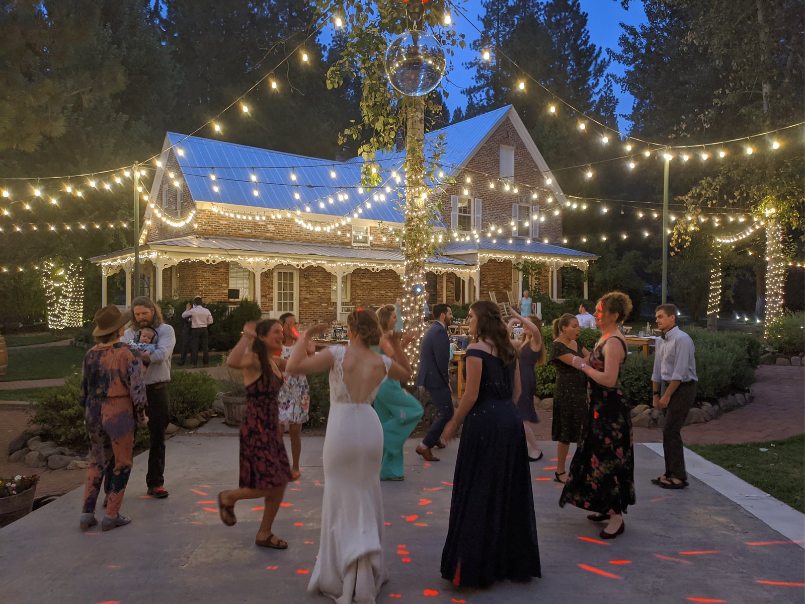 Lauren dances with her guests at dusk under the string lights