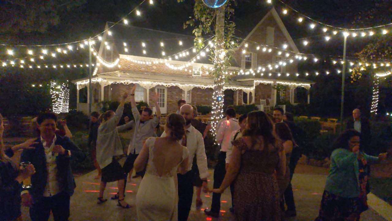 Lauren dances with her guests under the string lights at night
