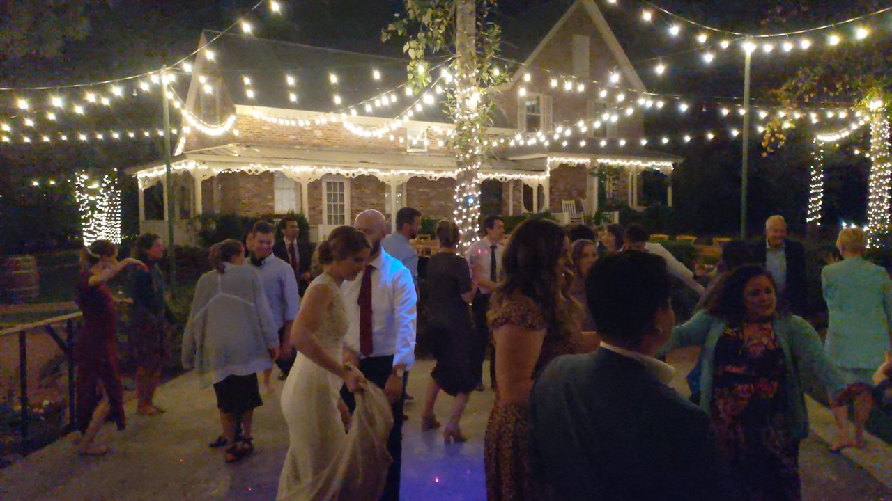 Lauren dances in the middle of a full dance floor in front of the brick house
