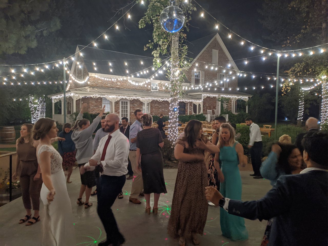 Mark dances with his guests under the string lights, Lauren beside him