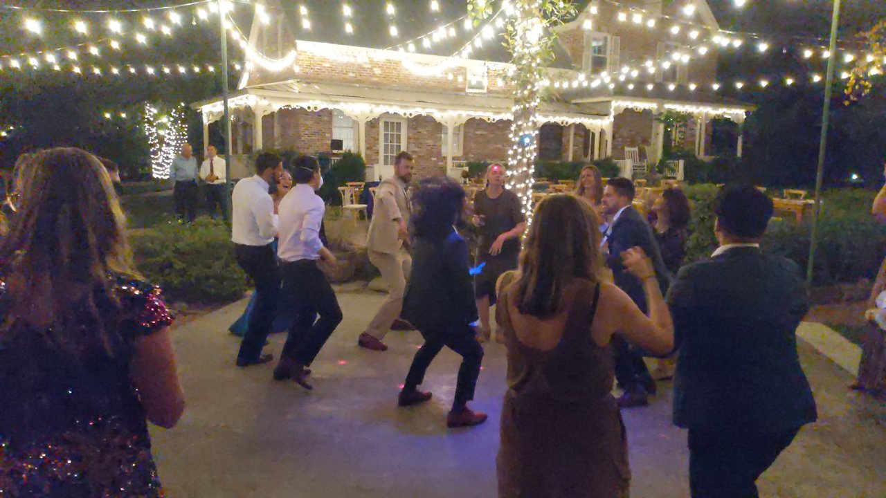 Guests dance on the patio in front of the glowing brick house