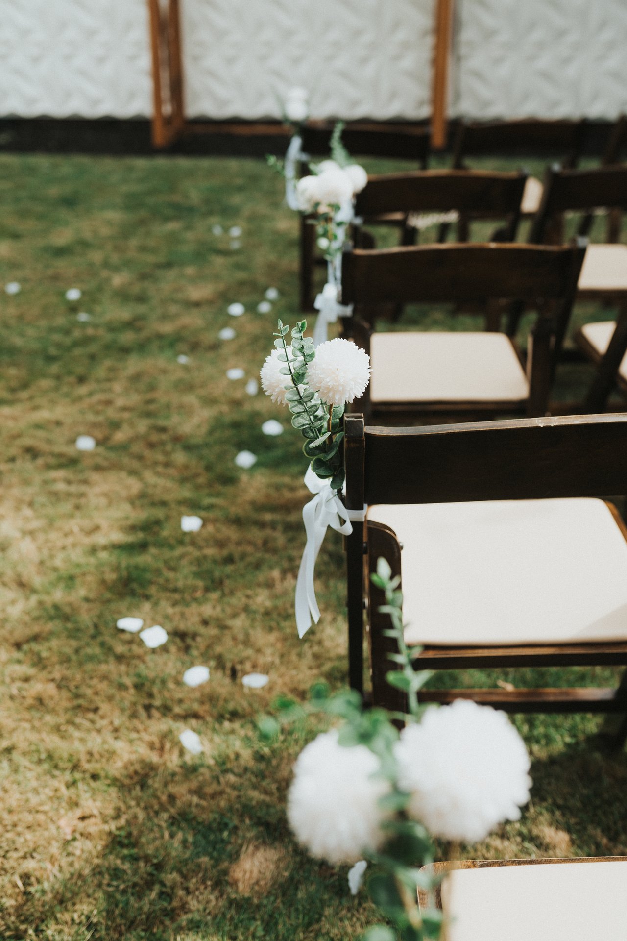 White flowers lining the aisle chairs in the backyard