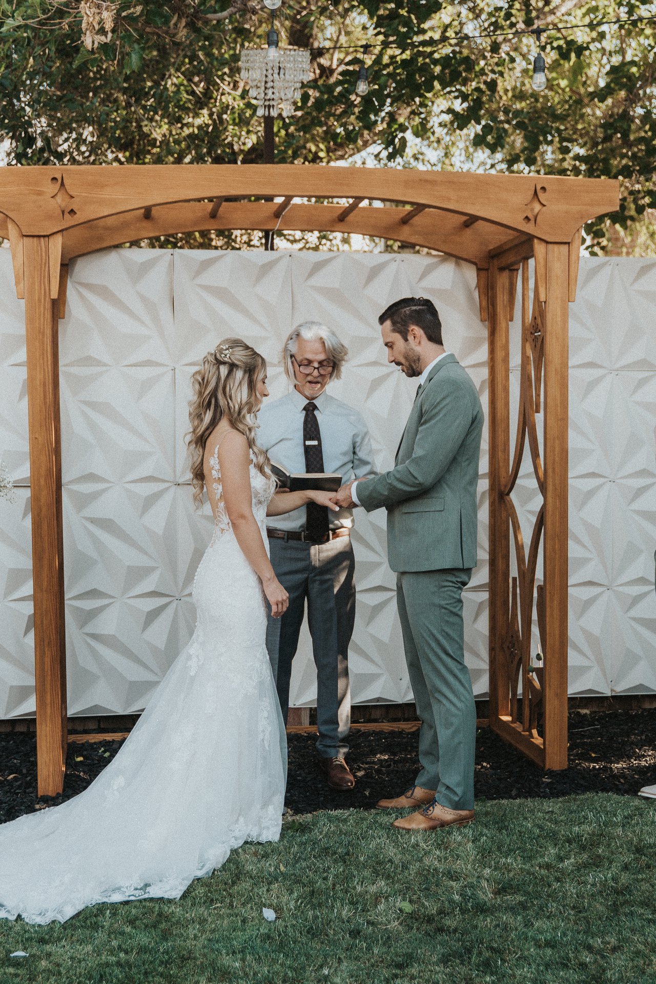 Lexy and Jeremy hold hands as the officiant reads