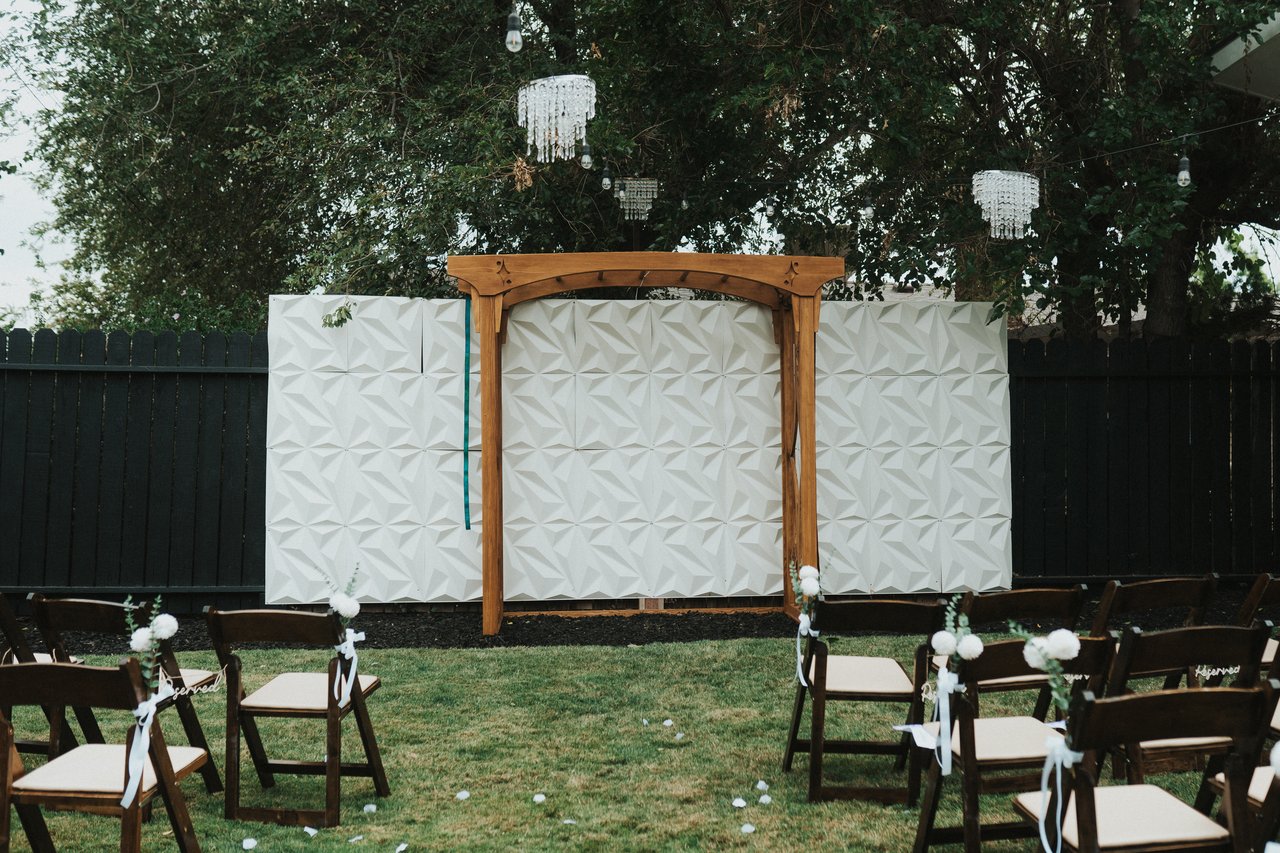 The wooden arbor and chairs set for the backyard ceremony