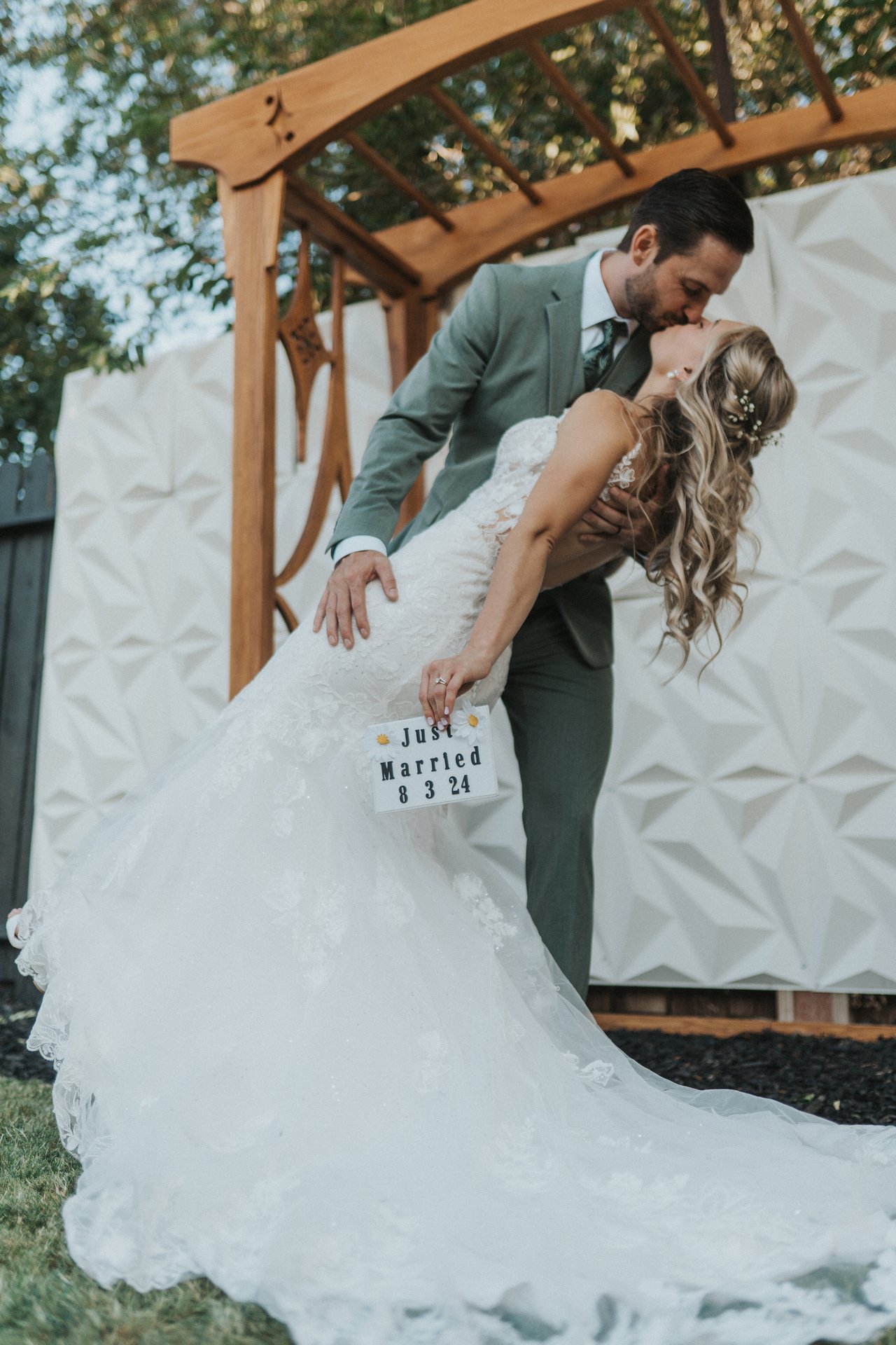 Jeremy dips Lexy as she holds the Just Married sign