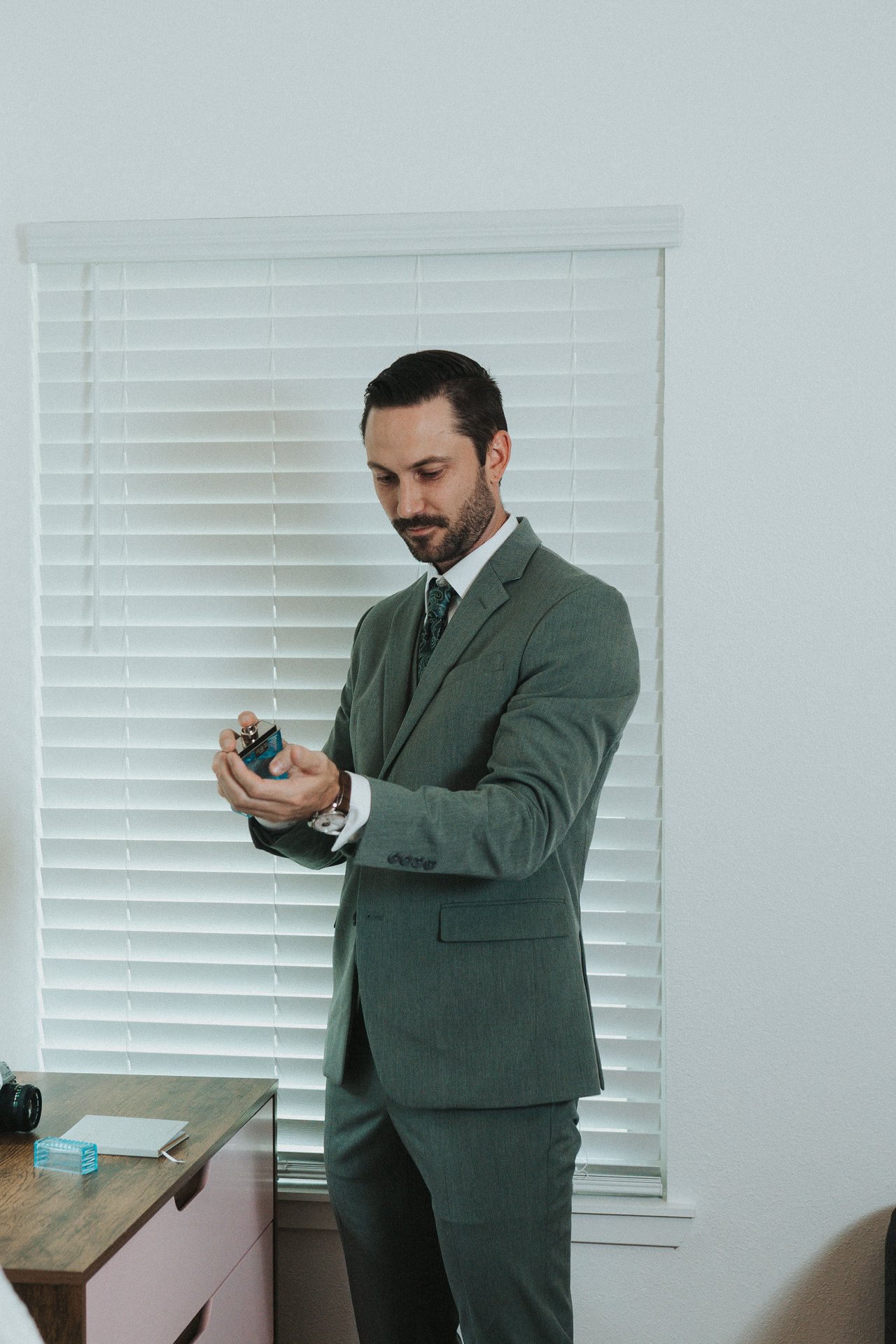 Jeremy putting on cologne by the window