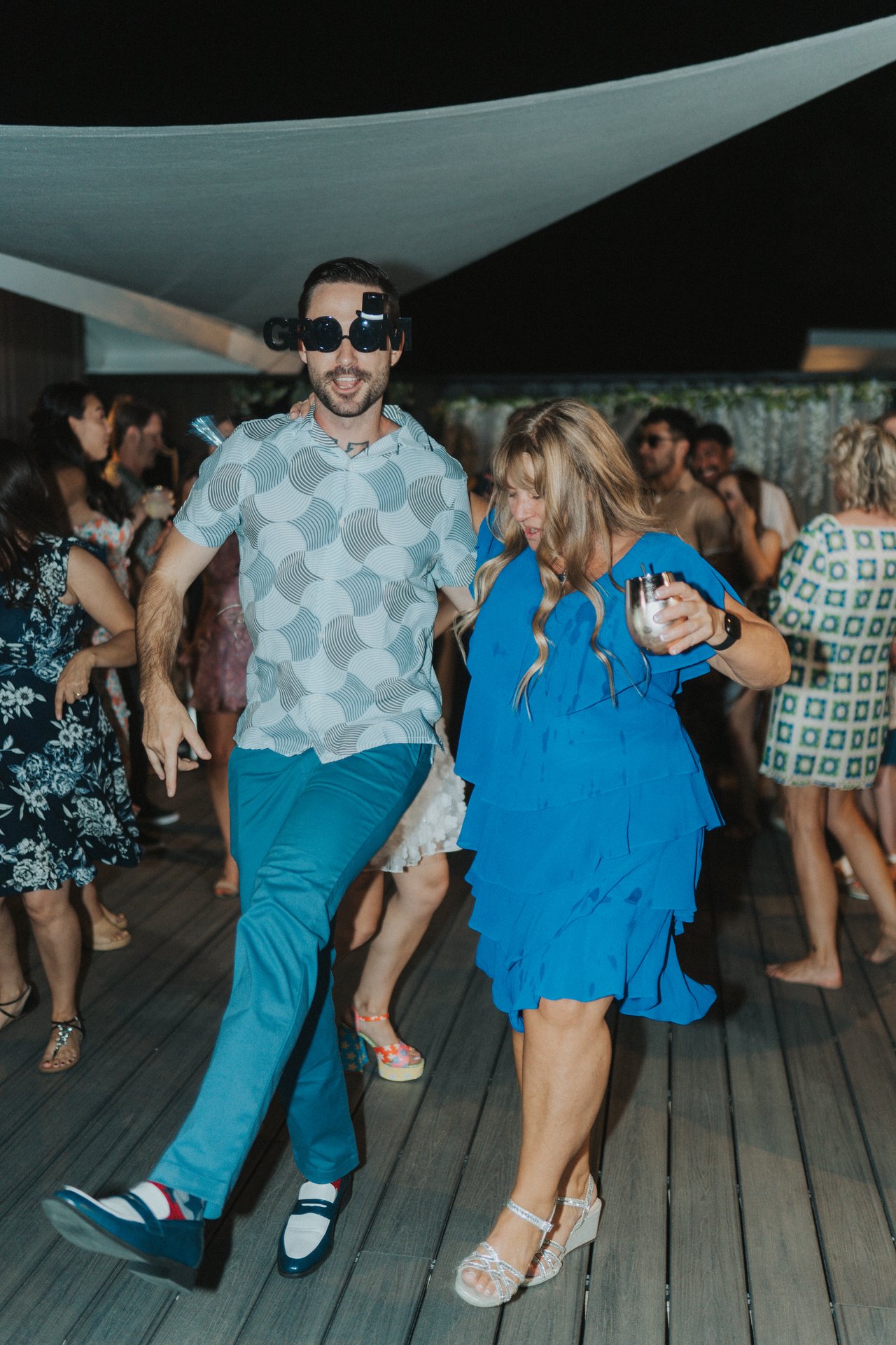 Jeremy kicks out a step beside a guest in a blue dress