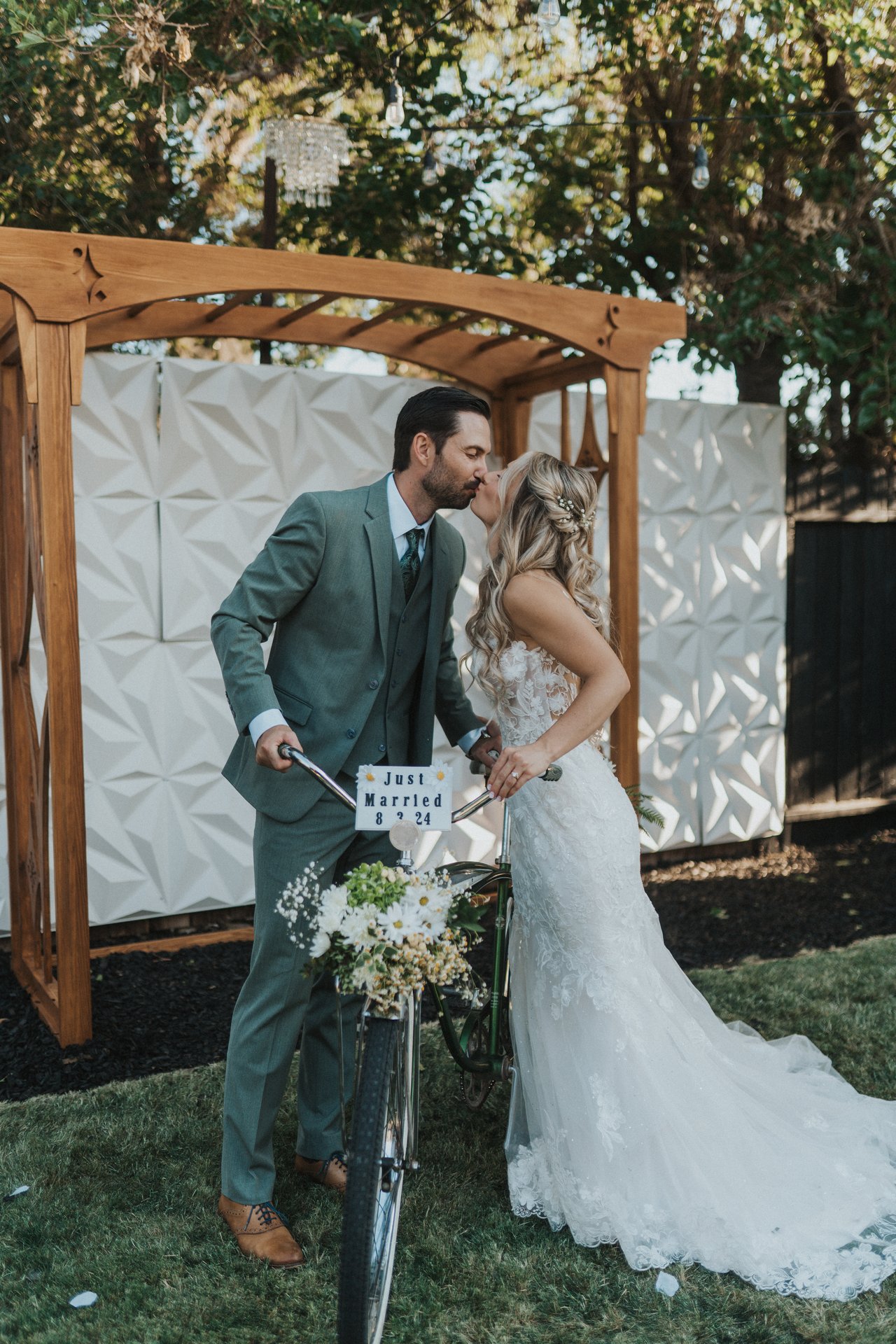 Lexy and Jeremy kiss over the bike with the Just Married sign
