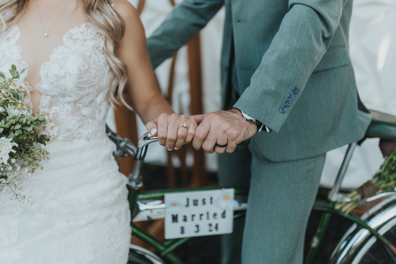 Lexy and Jeremy hold hands over the bike with the Just Married sign