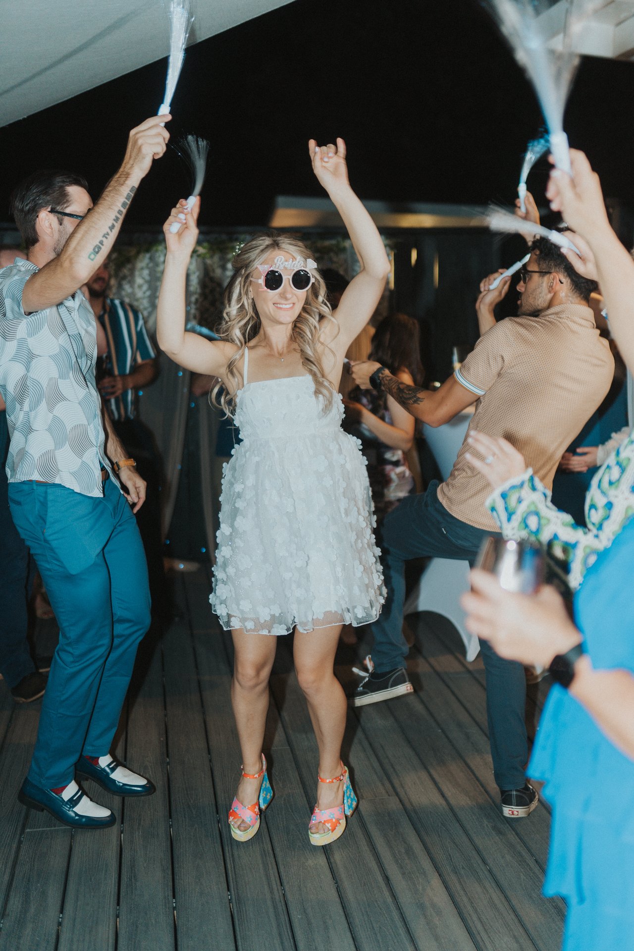 Lexy dancing with her arms up in white sunglasses