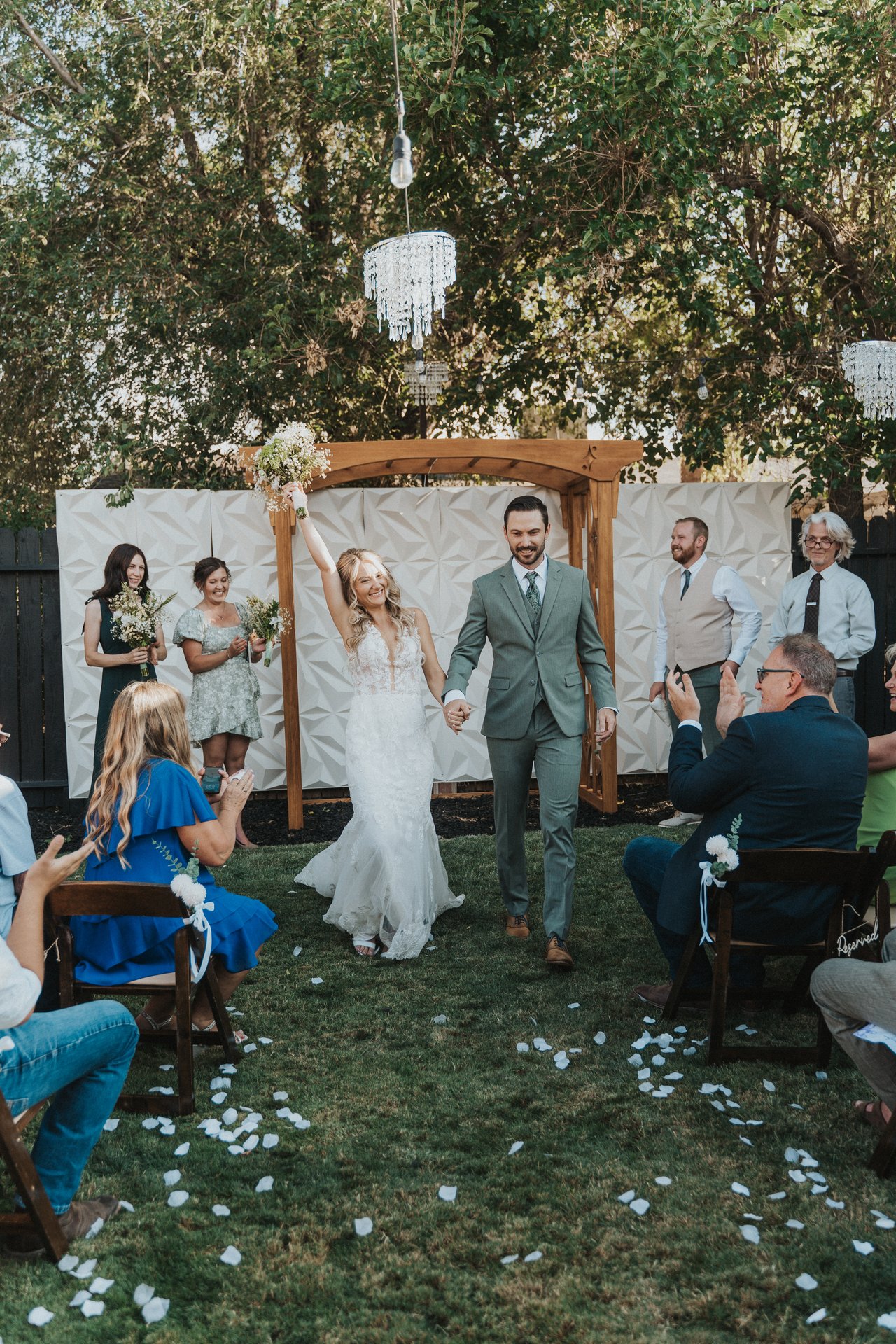 Lexy raises her bouquet as they walk back up the aisle