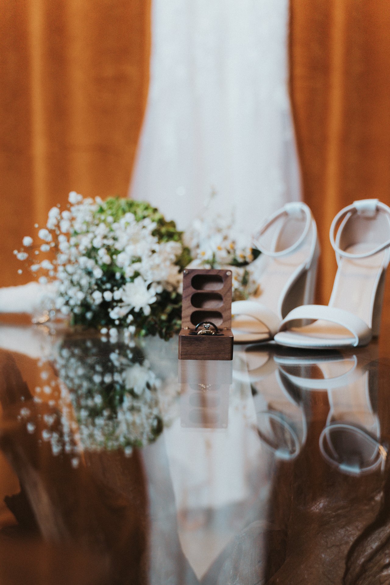 Wedding rings, bridal heels and baby's breath on a glass table