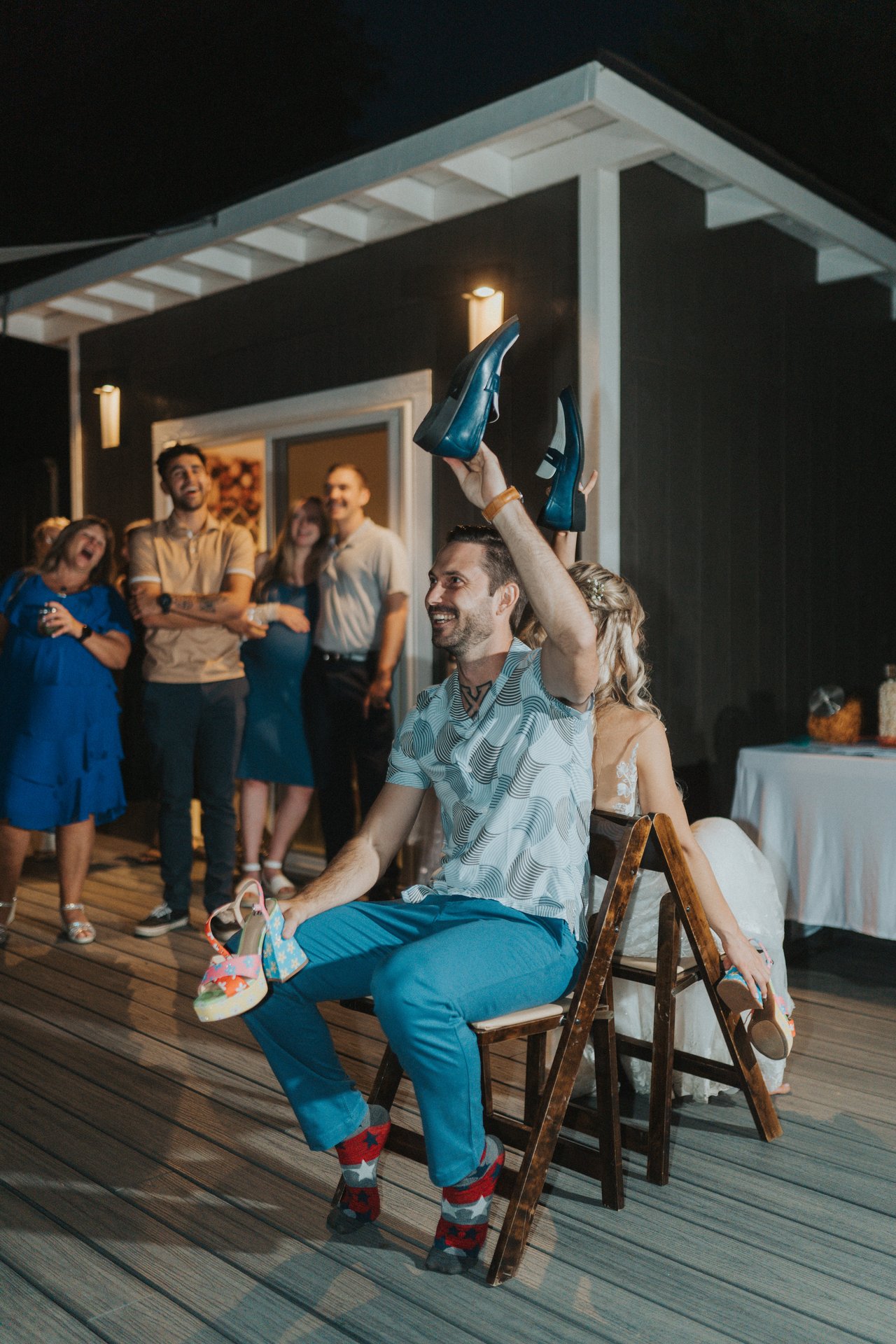 Jeremy raises a shoe while friends watch from the porch
