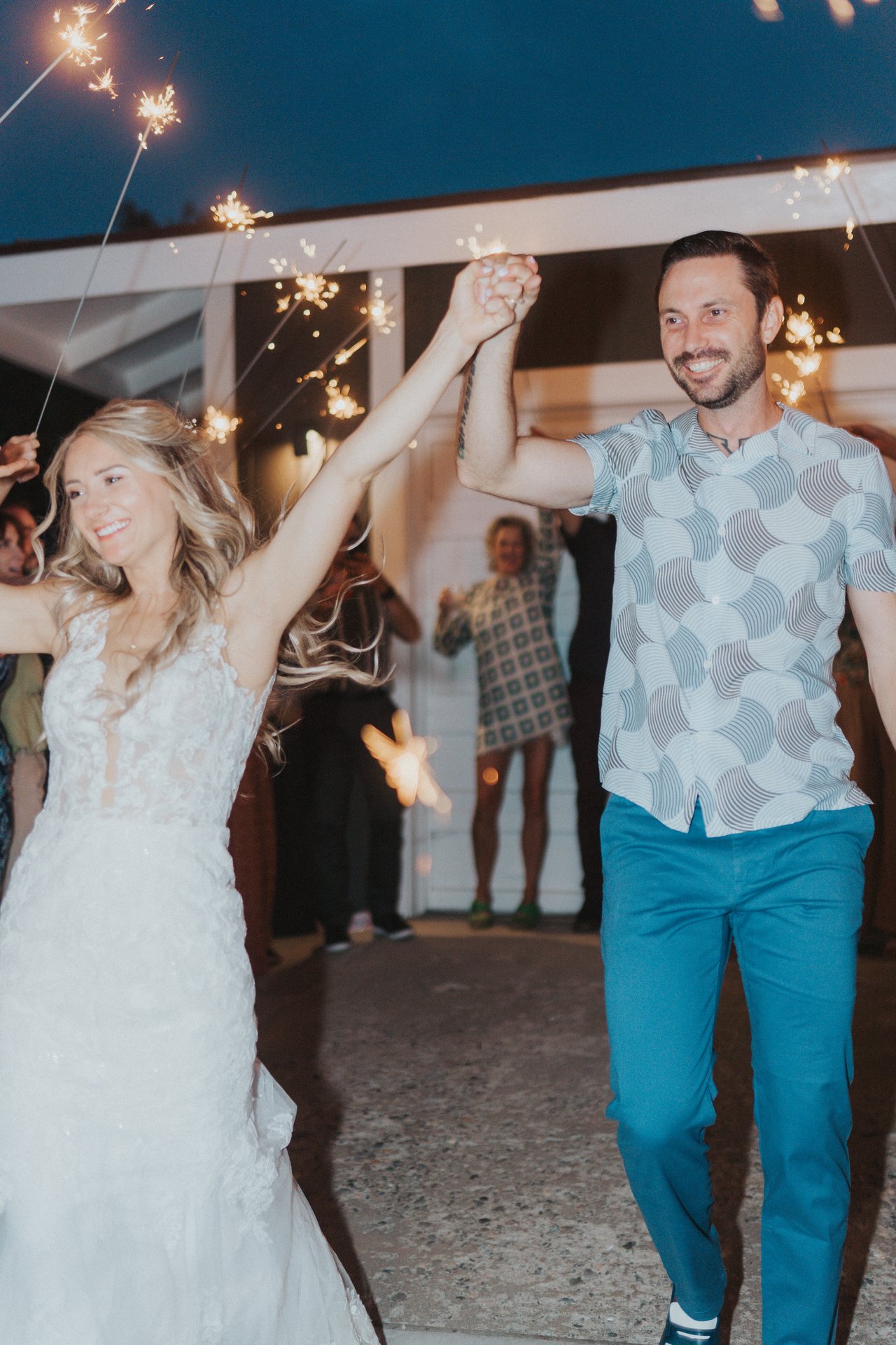 Lexy and Jeremy raise their hands as guests hold sparklers