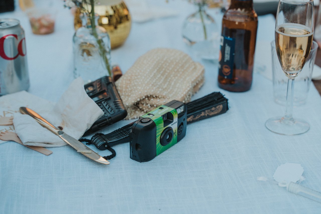 A disposable camera and a glass of champagne on a guest table