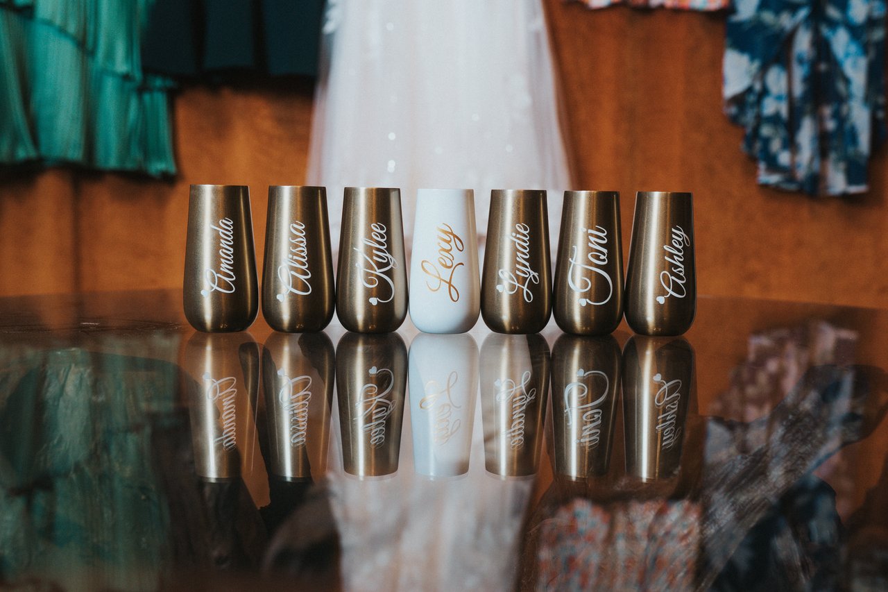 Engraved tumblers for the bridal party lined up on the glass table
