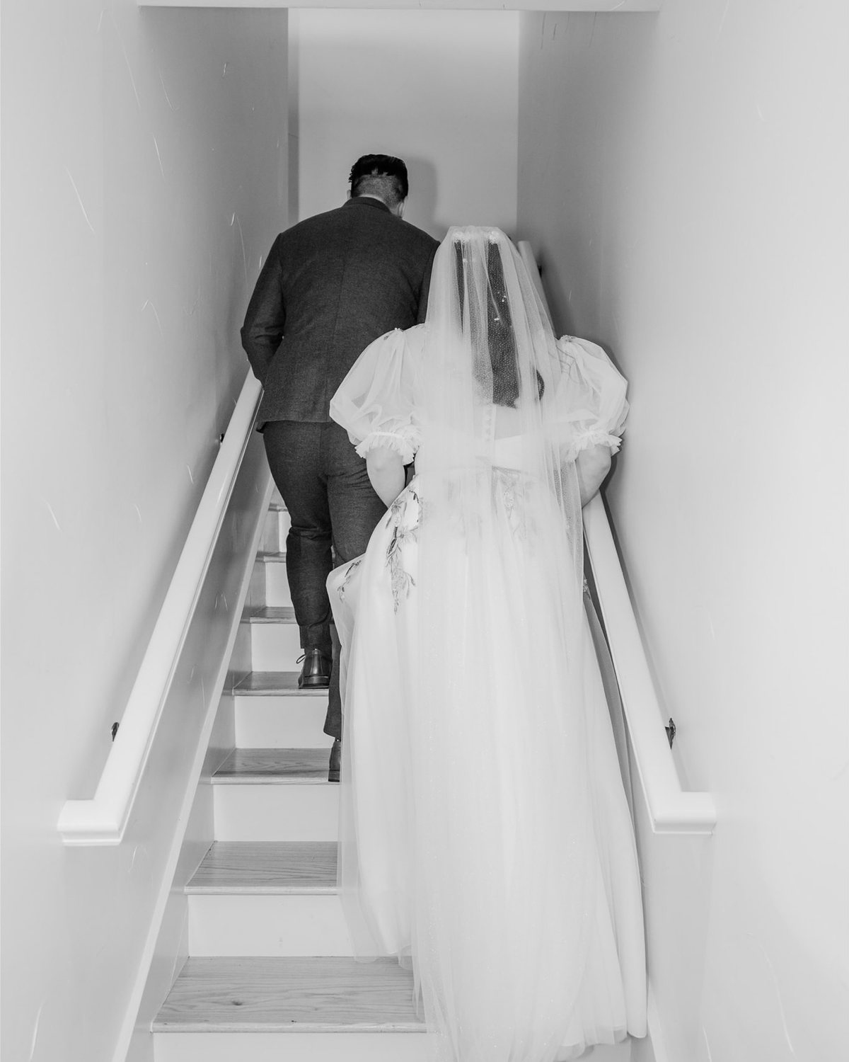 Madison and Adam walk up the stairs together, in black and white
