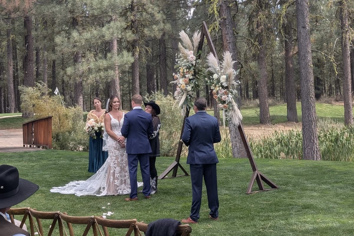 Molly and Matt at the pampas grass arch during their ceremony in the pines at Chalet View Lodge