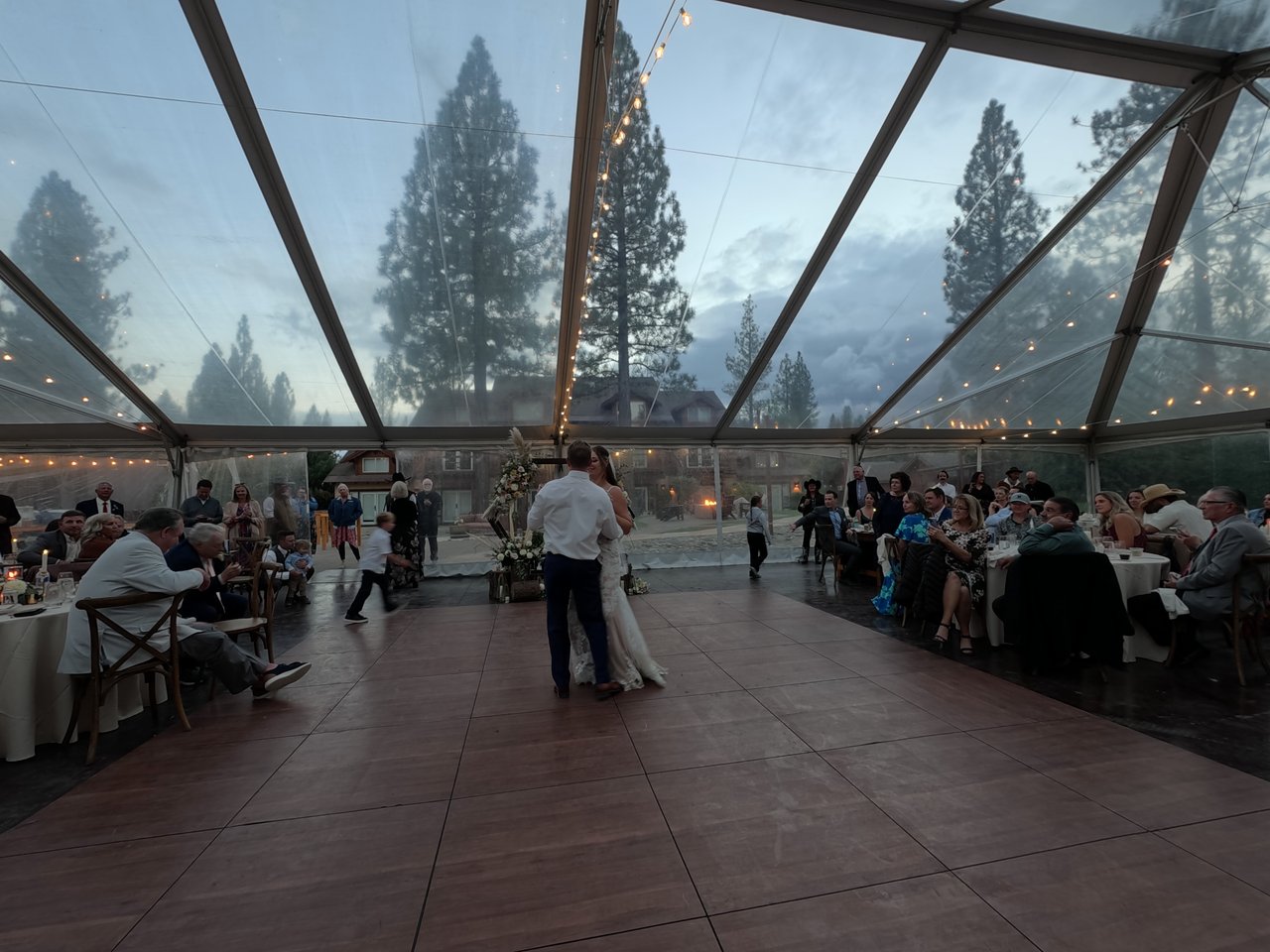 Molly dances with her father under the clear tent at dusk, the pines showing through the roof