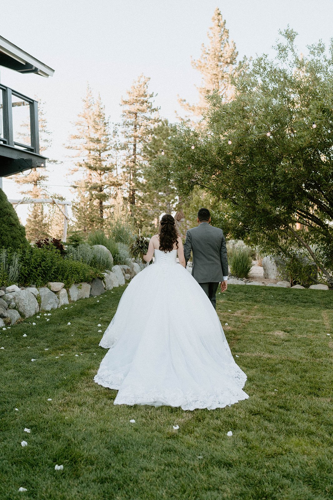 Montse's ball gown trails across the lawn as she walks behind Jason