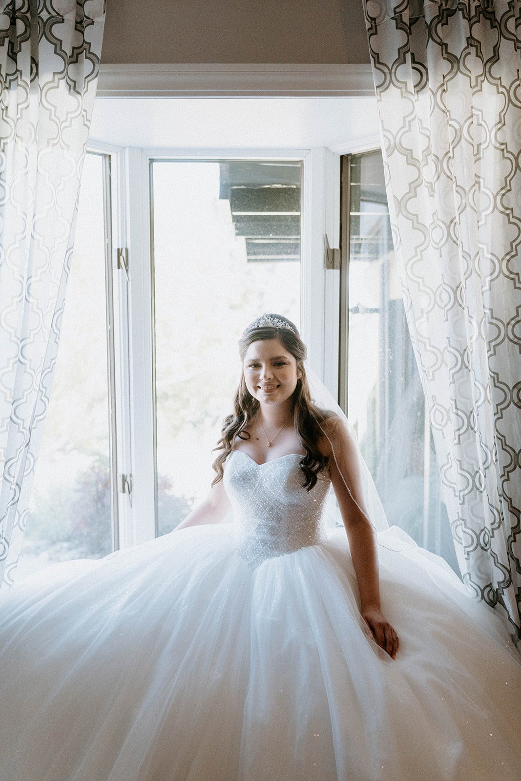 Montse sits in her ball gown by the bright window, in black and white