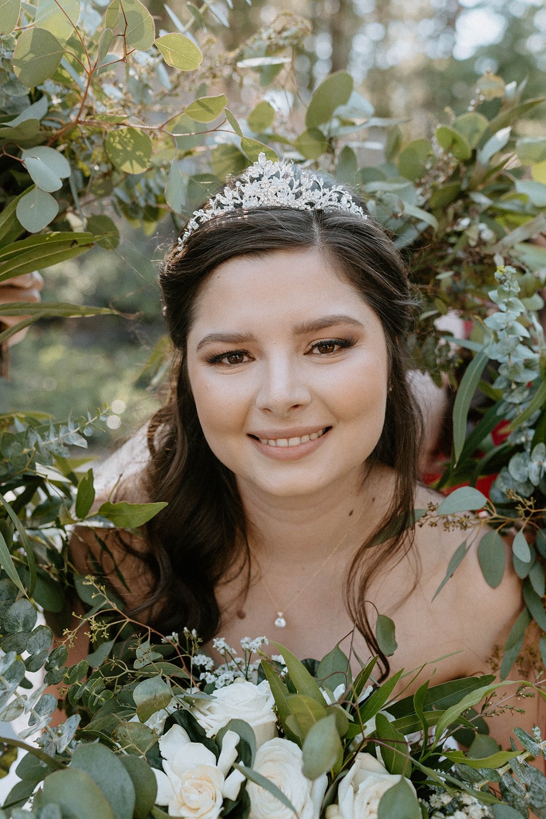 Montse smiles in her tiara framed by greenery