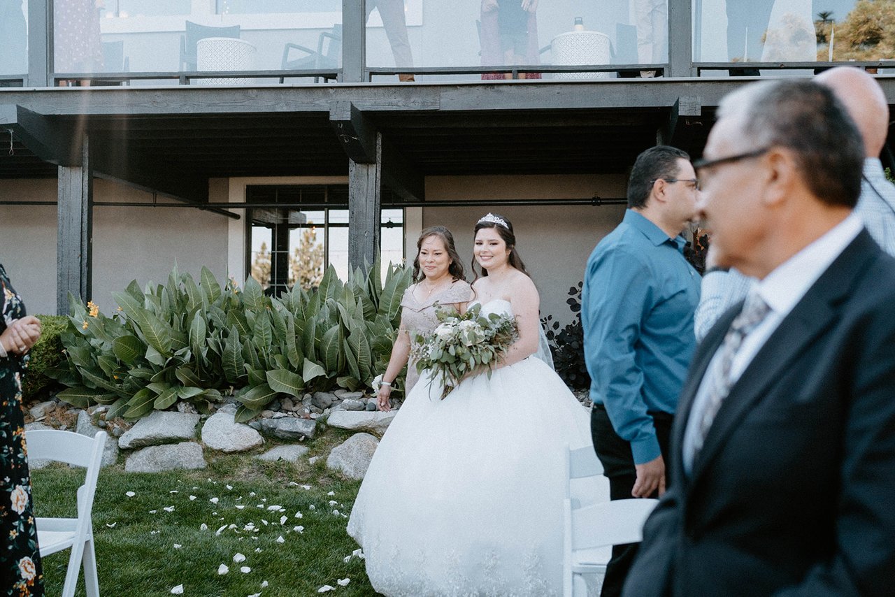 Montse walks in on the arm of her family as guests turn to see her