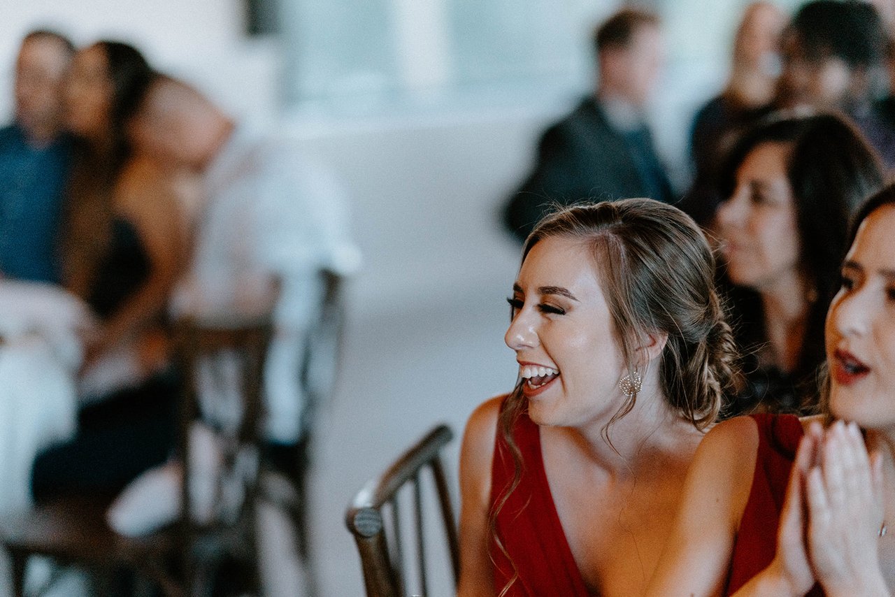 A bridesmaid in red laughs at the reception