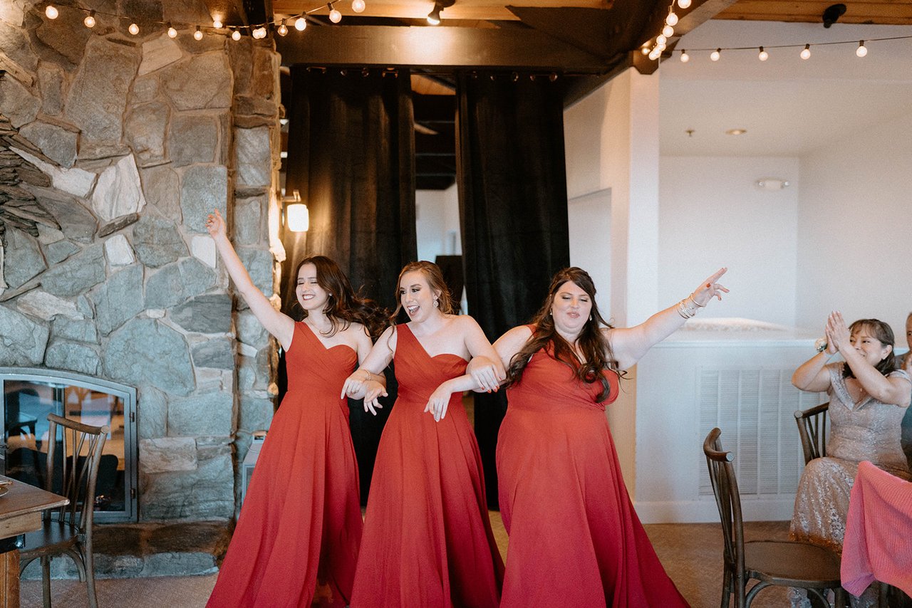 The bridesmaids in red dance into the reception