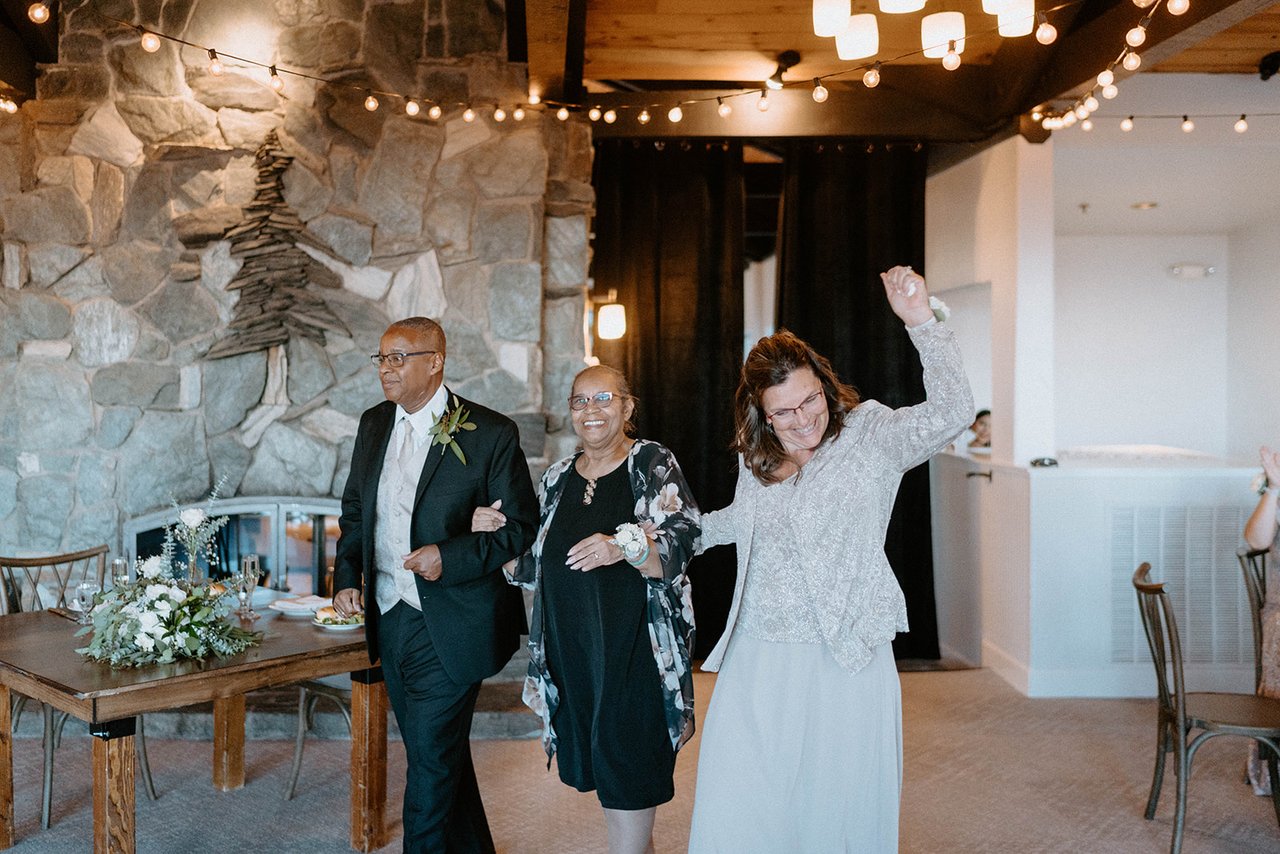 Family members raise their arms as they dance into the reception