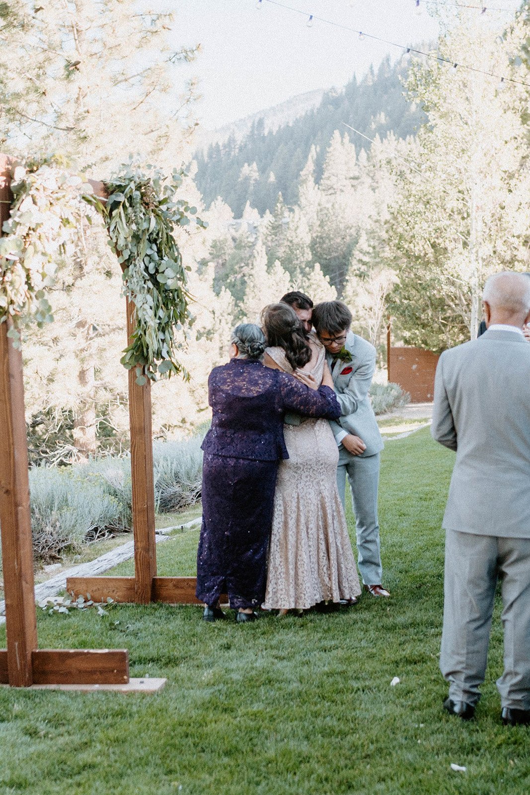 Family hugs at the arch after the ceremony