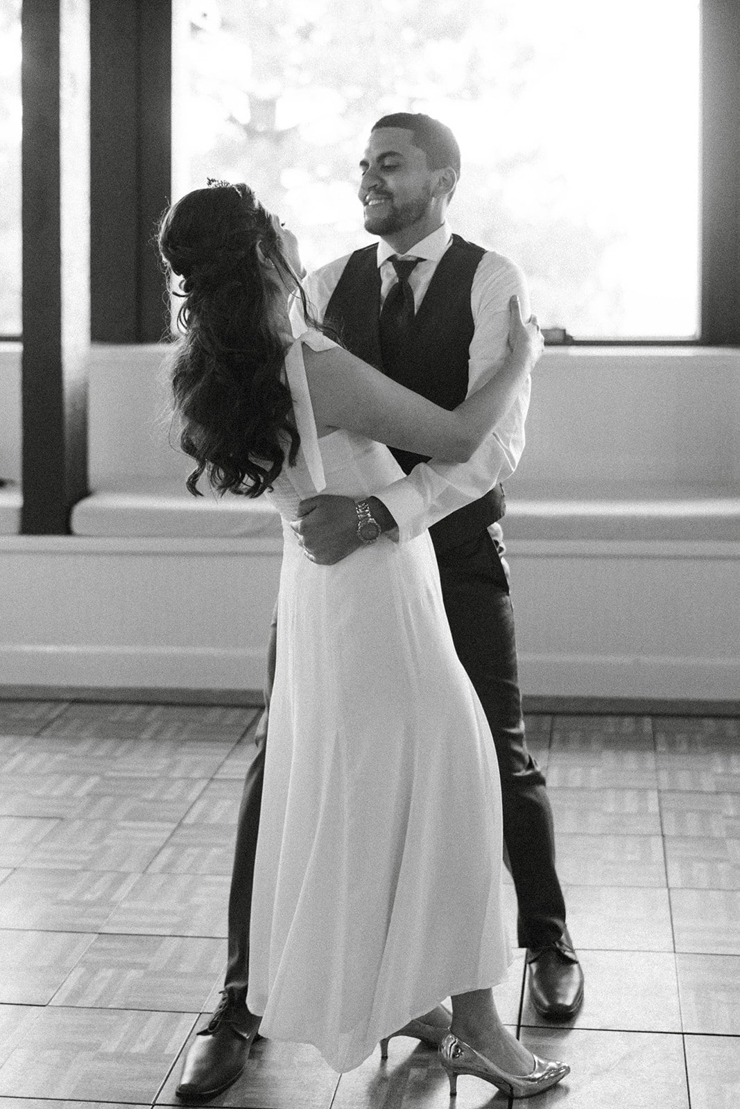 Montse and Jason dance close by the windows, in black and white