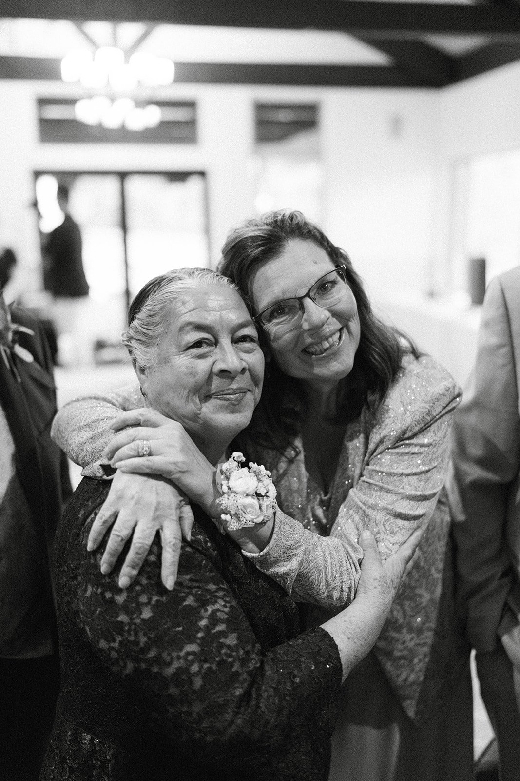 Two guests share a hug, in black and white