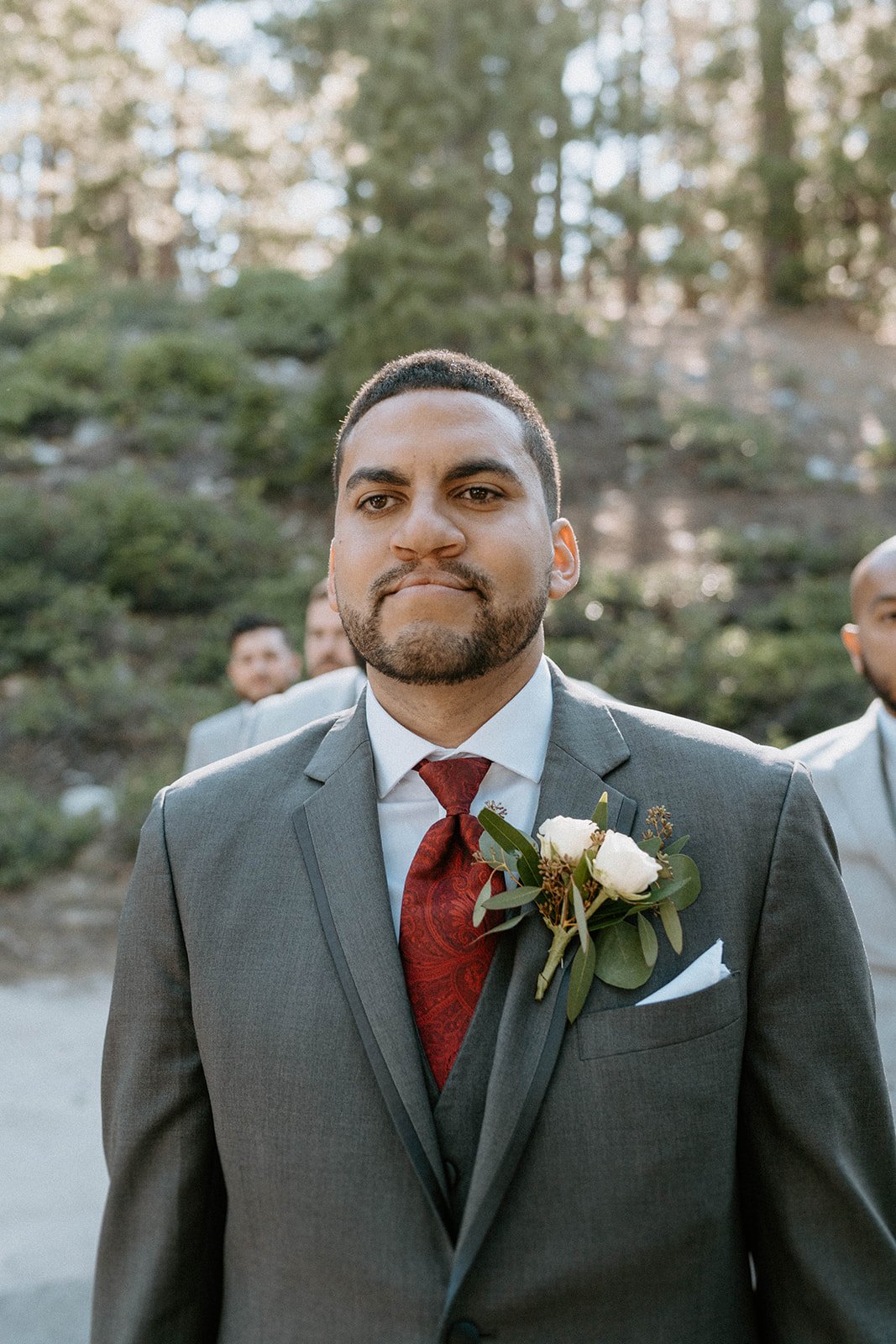 Jason in his grey suit and red tie under the pines