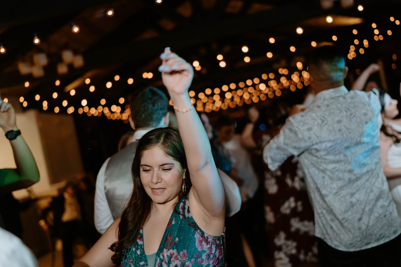 A guest in green dances with her hand in the air