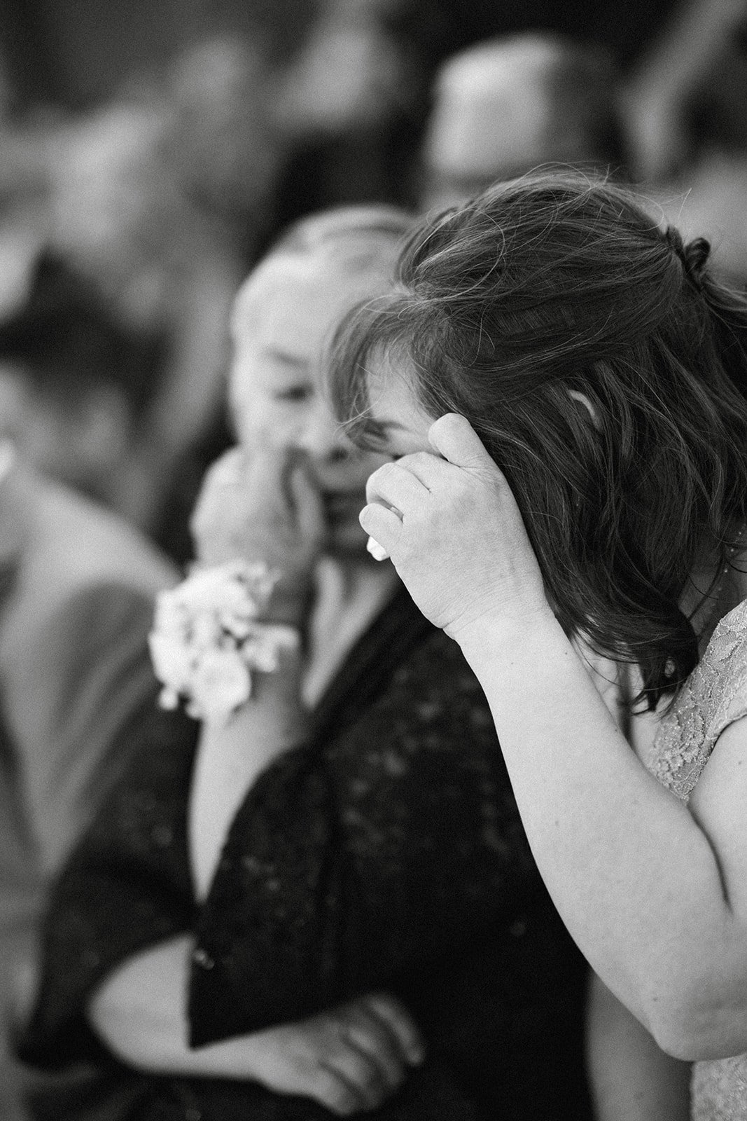 A guest wipes away tears during the vows, in black and white