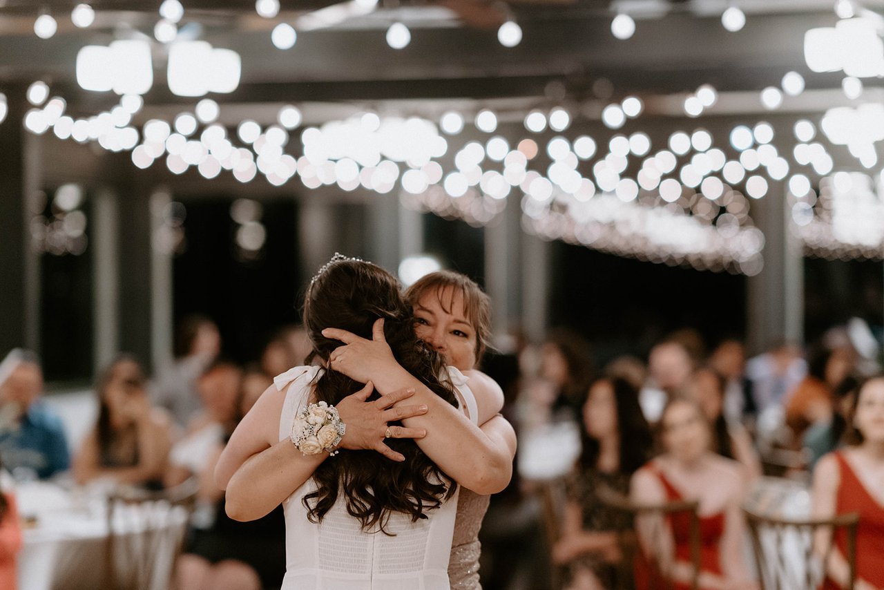 Montse and her mom embrace under the string lights
