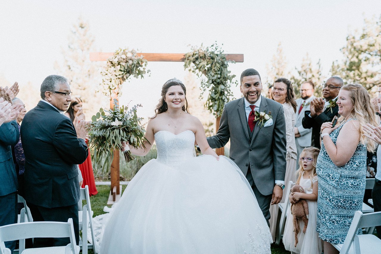 Montse and Jason walk back up the aisle as guests cheer