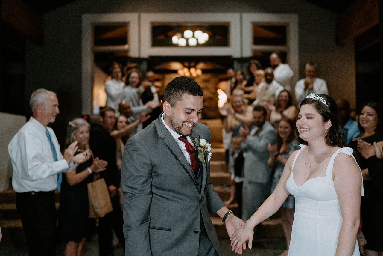 Montse and Jason walk out hand in hand past cheering guests