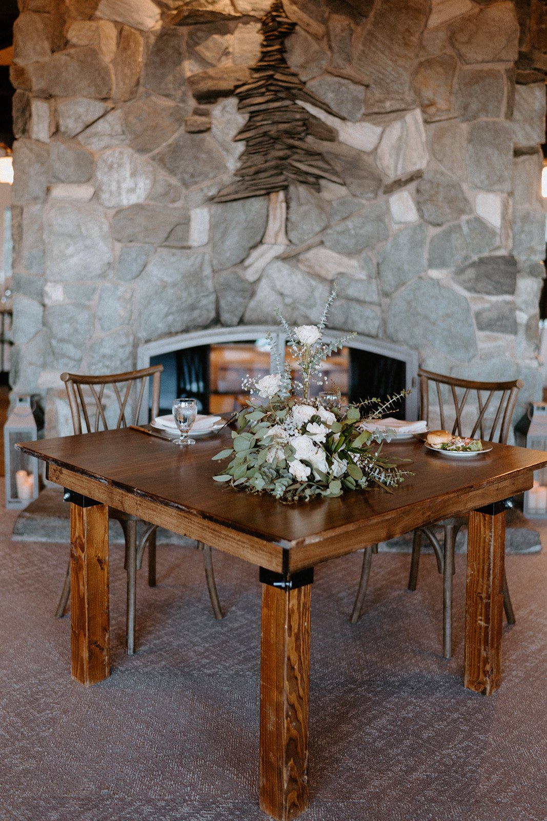 The sweetheart table in front of the stone fireplace