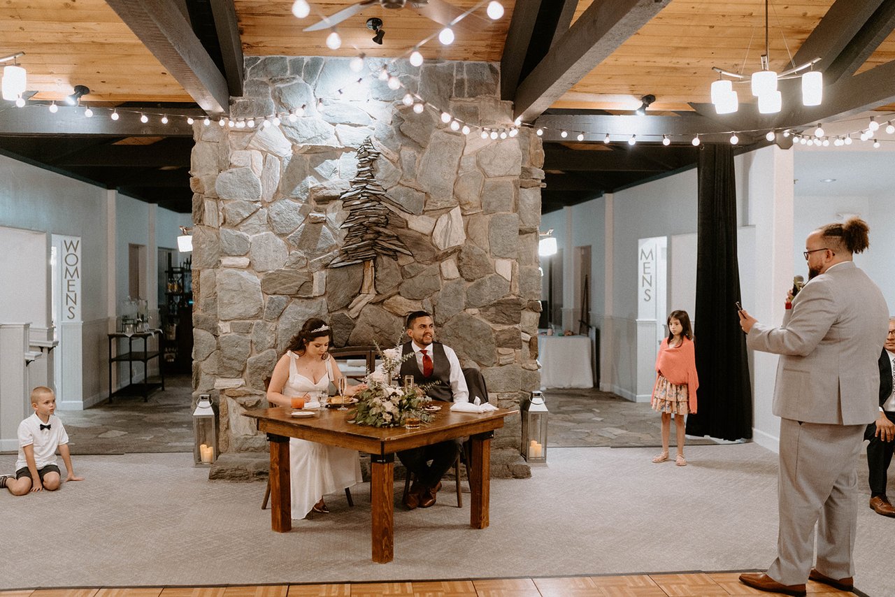 The best man gives a toast in front of the stone fireplace