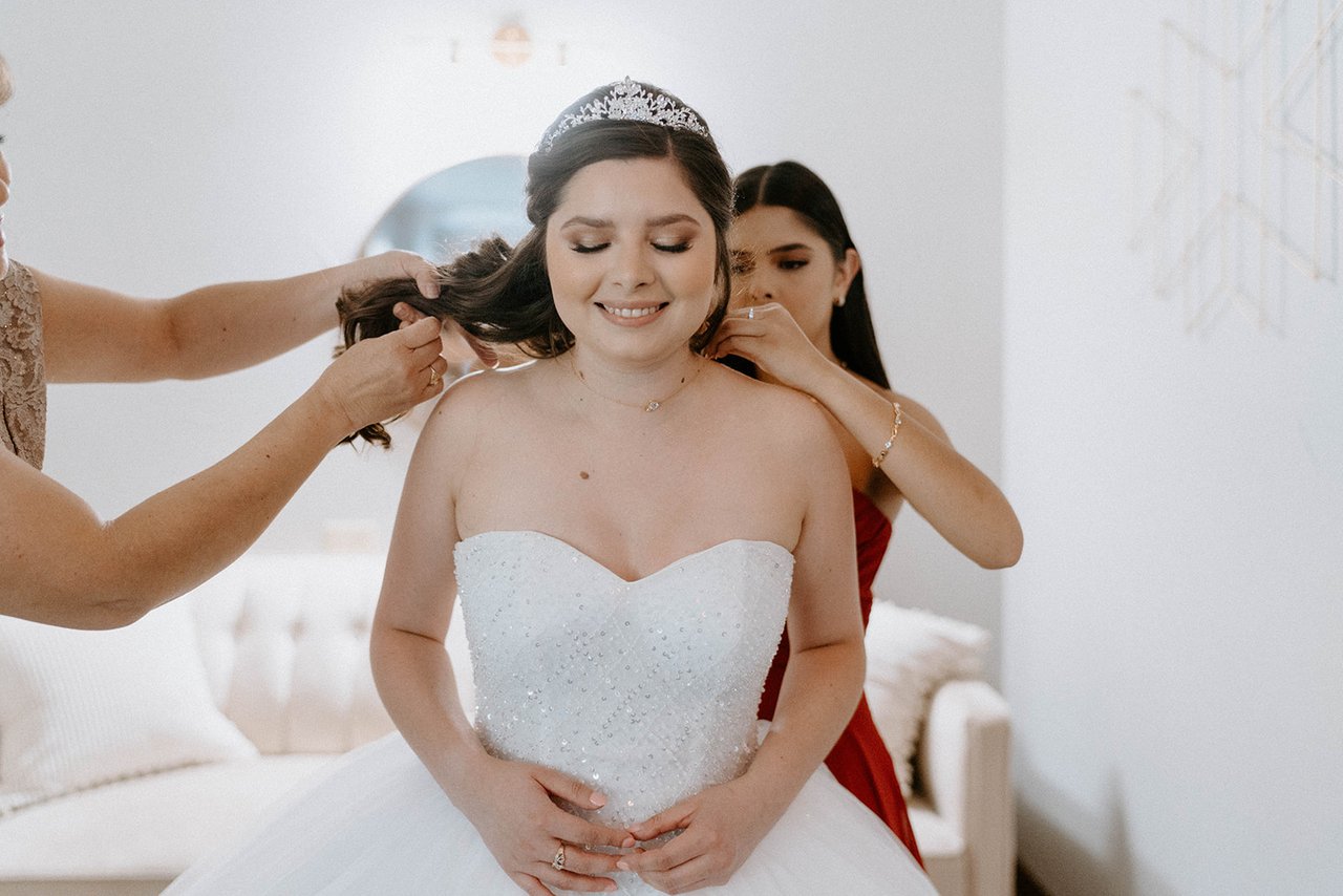 Montse smiles with her eyes down as her bridesmaids pin her hair