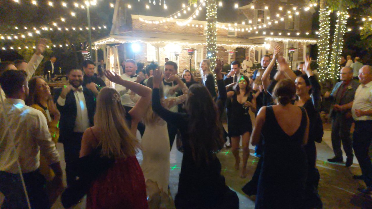 Guests throw their hands up on the courtyard dance floor under the string lights