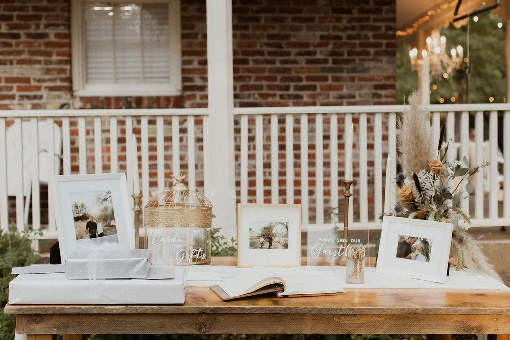 Framed photos, a card box and the guest book on a table by the brick house porch, photo by Kay Kroshus Photography