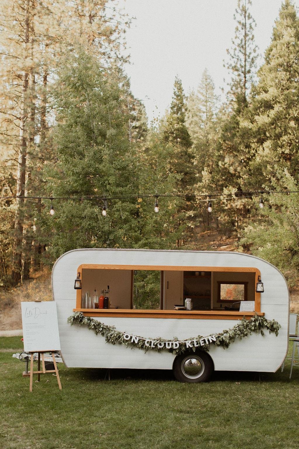 A vintage bar trailer with an On Cloud Klein garland on the lawn, photo by Kay Kroshus Photography